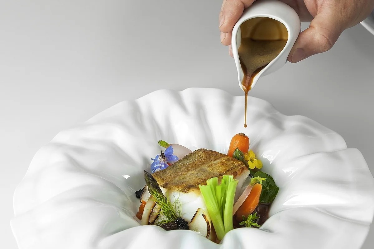 Sauce being poured over a plated dish at the table at Arcadas, Coimbra
