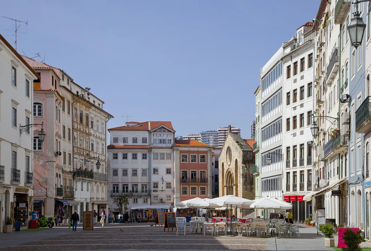 A narrow Coimbra tasca with marble tables and handwritten notes covering the walls