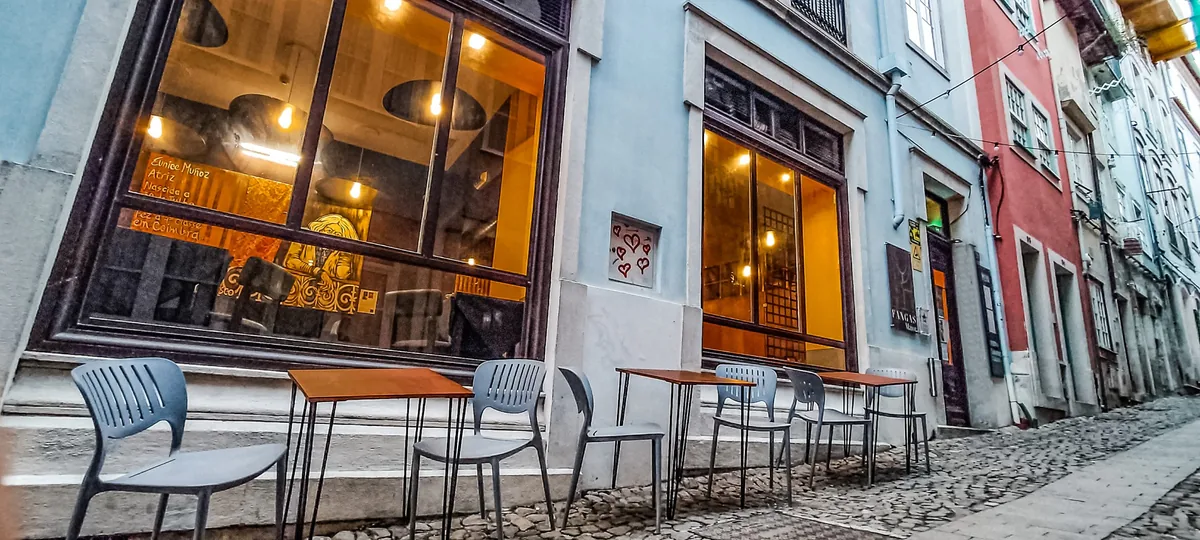 Fangas Mercearia Bar lit at night, with tables out on the sloping street