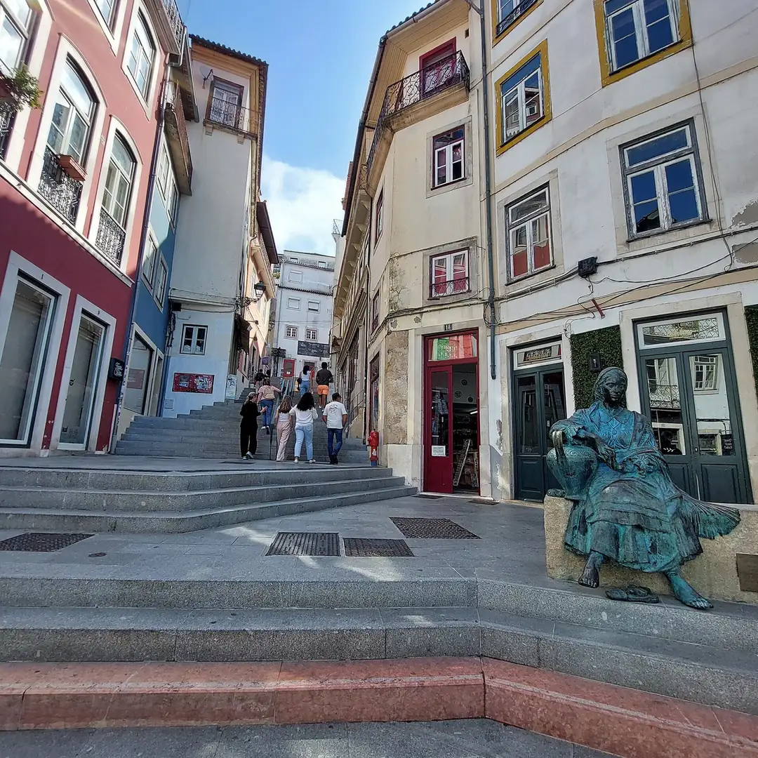 The stepped lane of Rua do Quebra-Costas climbing from the Arco de Almedina toward the Old Cathedral