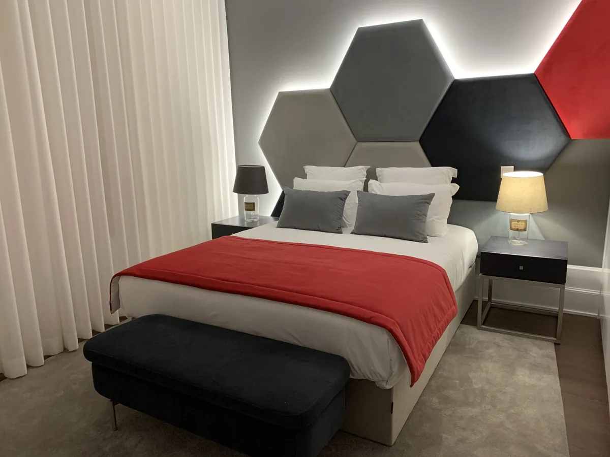 A bedroom with a hexagonal padded headboard at Pharmacia GuestHouse, Coimbra